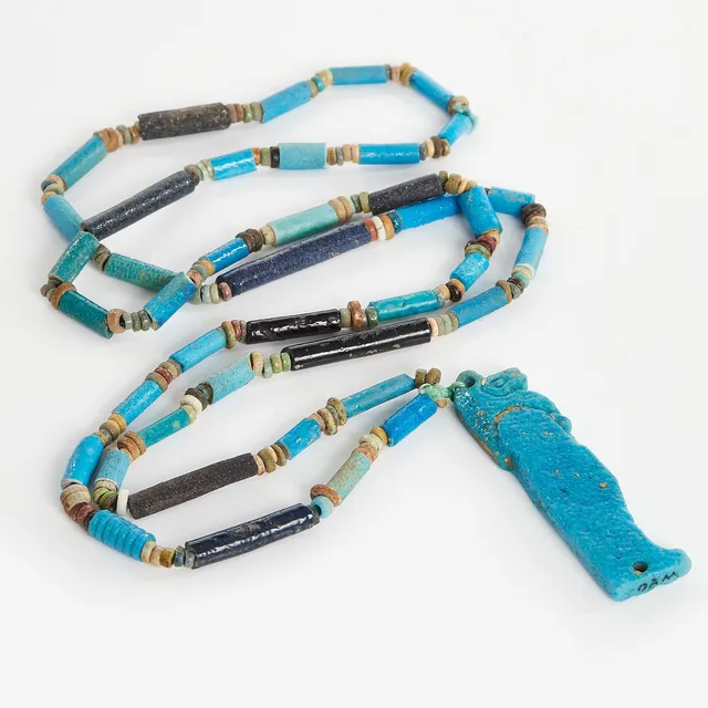 AMULET, Egypt, Late Period (664-332 BC). Funerary amulet in blue faience depicting Qebehsenuef, one of the sons of Horus and protector of the internal organs. L: 6cm. The amulet has been attached later to a string of ancient faience beads.