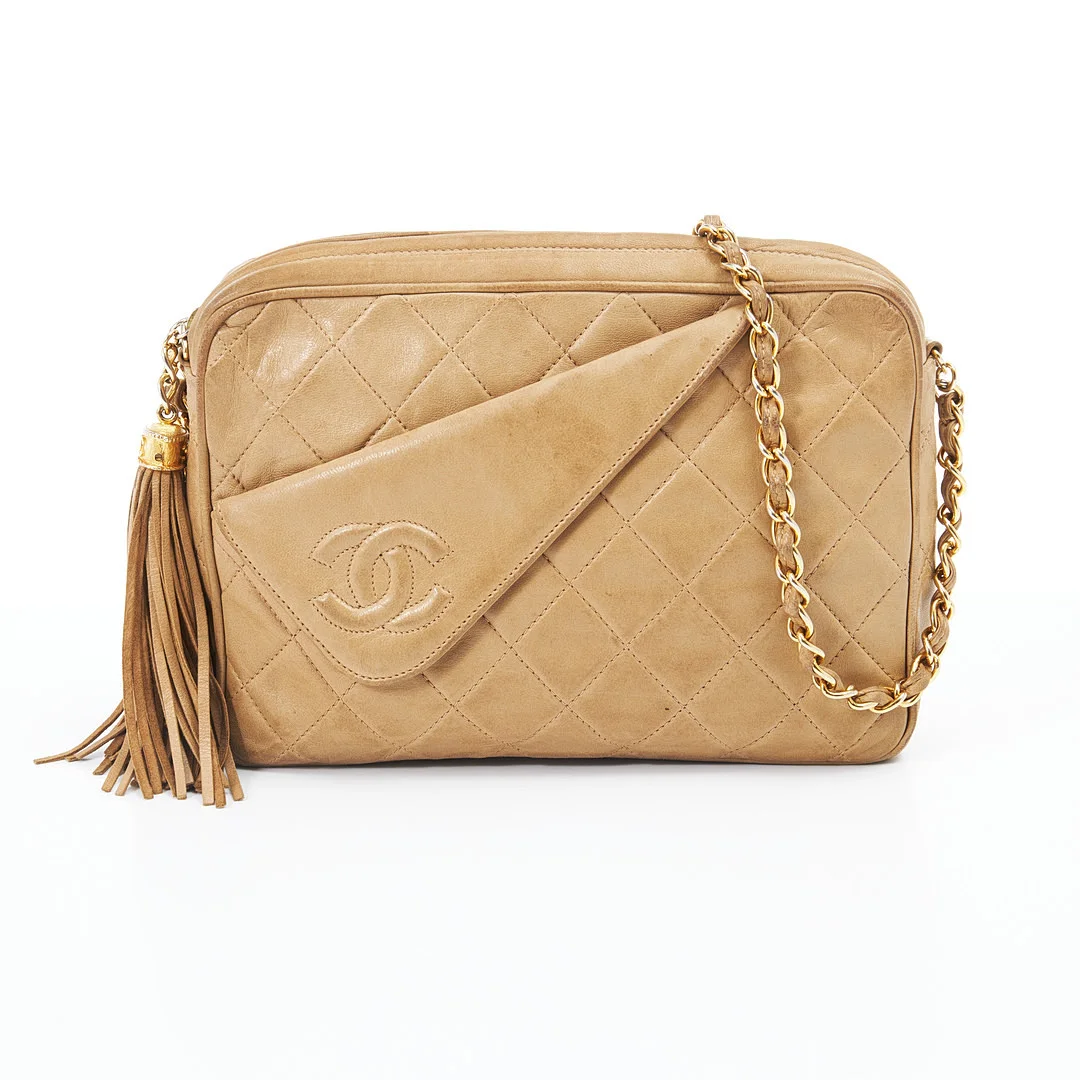 CHANEL, "Camera crossbody tassel bag", beige quiltat lammskinn, klassisk metallkedja med inträtt läder, invändigt med 2 fack varav ett med dragkedja, stänges med dragkedja med dekor av tofs, nervikt ytterfack med dekor av CC-logo, datecode år 1986-1988. — Vintage & Designer Fashion — Stockholms Auktionsverk Magasin 5
