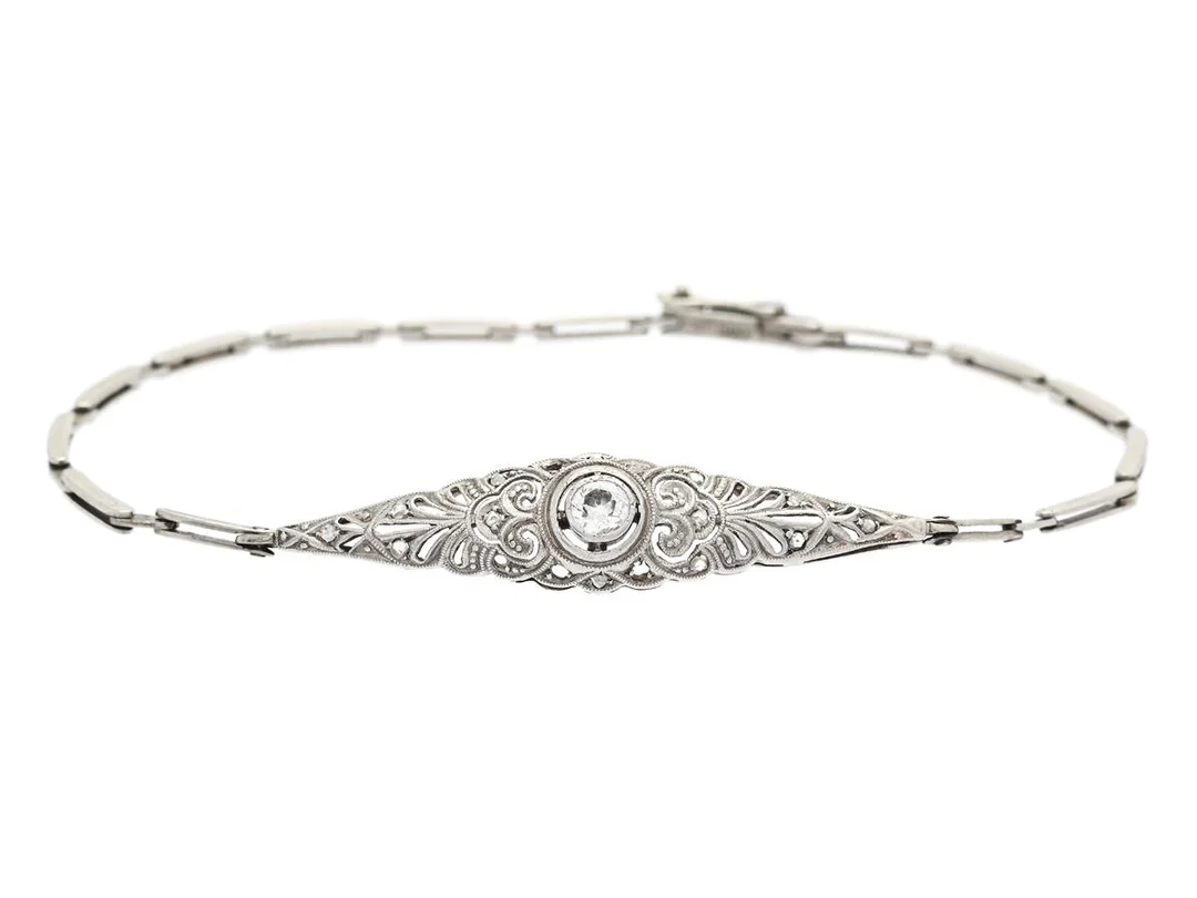 ARMBAND, 14K vitguld / platina, gammalslipad diamant ca 0,15 ct, 14 små fasetterade diamanter (ytterligare 4 saknas), längd 17,5 cm, vikt 4,4 g. — Smycken/Armband — Kaplans