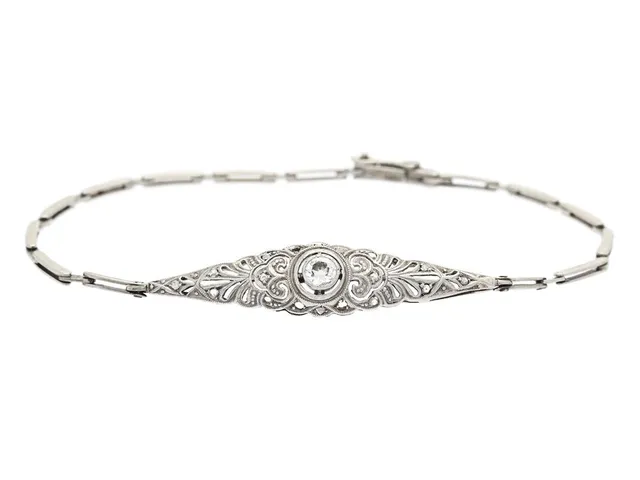 ARMBAND, 14K vitguld / platina, gammalslipad diamant ca 0,15 ct, 14 små fasetterade diamanter (ytterligare 4 saknas), längd 17,5 cm, vikt 4,4 g.