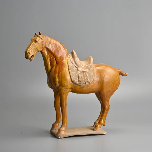 A CHINESE GLAZED POTTERY SADDLED HORSE, TANG DYNASTY OR LATER.