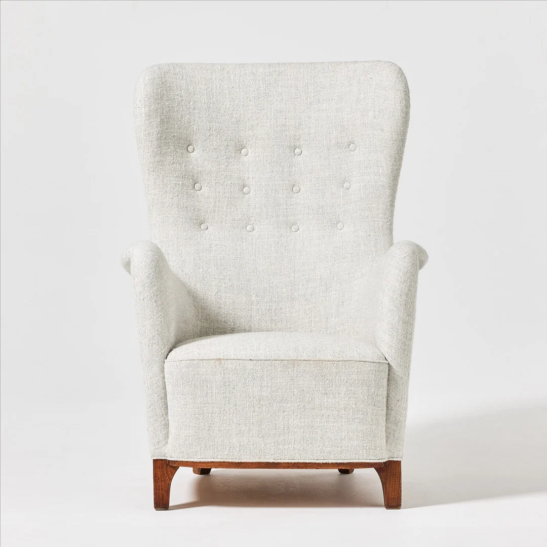 FRODE HOLM. Fåtölj, för Illums Bolighus, stoppad rygg och sits klädda i ljust tyg, ryggen med klädda knappar, ben och sarg i betsad bok. — Armchairs & Chairs — Stockholms Auktionsverk Fine Art