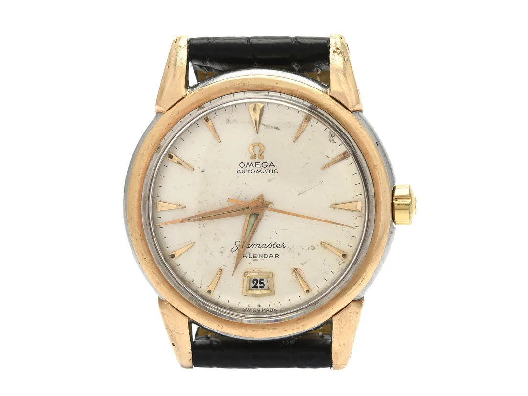 OMEGA, Seamaster, Calendar, Cal 353, Serie nr. 13111140, Ref nr. KO 2627, Boett nr. 2627-14 SC, herrur, 35 mm, guld på stål (Staybrite), hammarautomat, plexiglas, datum, skadad urtavla, defekt, skadad boett, läderband, ca 1952. — Klockor/Omega — Kaplans