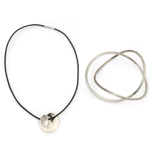 A bangle and pendant in sterling silver. Pendant set on black cord. Design no. 394. L. 42 cm. Made by Georg Jensen. (2)