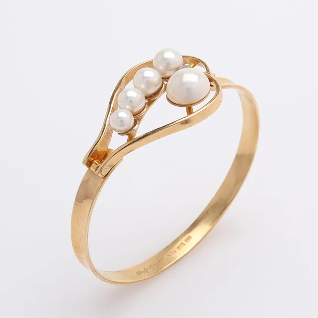 ELON ARENHILL. ARMRING, 18K GULD MED FEM STYCKEN PÄRLOR OCH EN BRILJANT, TOTAL VIKT 32,2 GRAM.