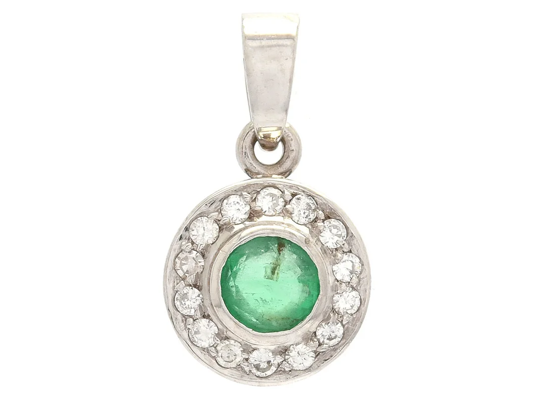 HÄNGE, 18K vitguld, smaragd ca 0,22 ct, 14 diamanter (13 briljantslipade och 1 åttkantslipad) ca 0,10 ctv, ca W-TCr/VS-SI, den åttkantslipade är skadad, vikt 1,4 g. — Smycken/Hänge — Kaplans
