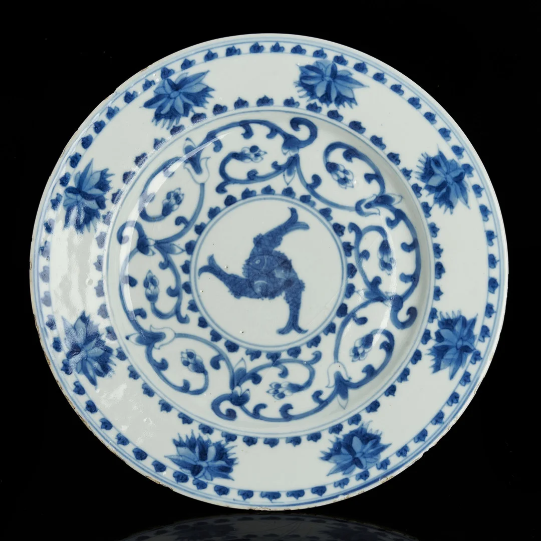 TALLRIK, porslin, Kina, dekor i underglasyrblått av blomster och tre sammanflätade fiskar (symbol för evigt välstånd och överflöd), Kangxi (1661-1722). — Ceramics & Porcelain — Crafoord Auktioner Stockholm