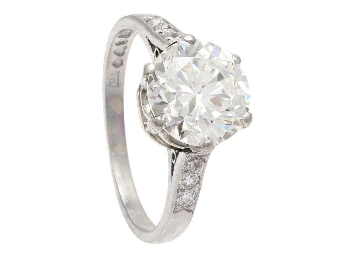 DAVID ANDERSEN & CO, ring, platina, briljantslipad diamant ca 2,30 ct, ca TCr(I)/VS2, 6 äldre briljantslipade diamanter ca 0,12 ctv, Stockholm 1945, stl 16,25+ mm, vikt 4,1 g, mittstenen har liten kulettfasett och liten inverterad natural vid rondisten, två sidostenar har nagg på kronan. — Smycken/Ring — Kaplans