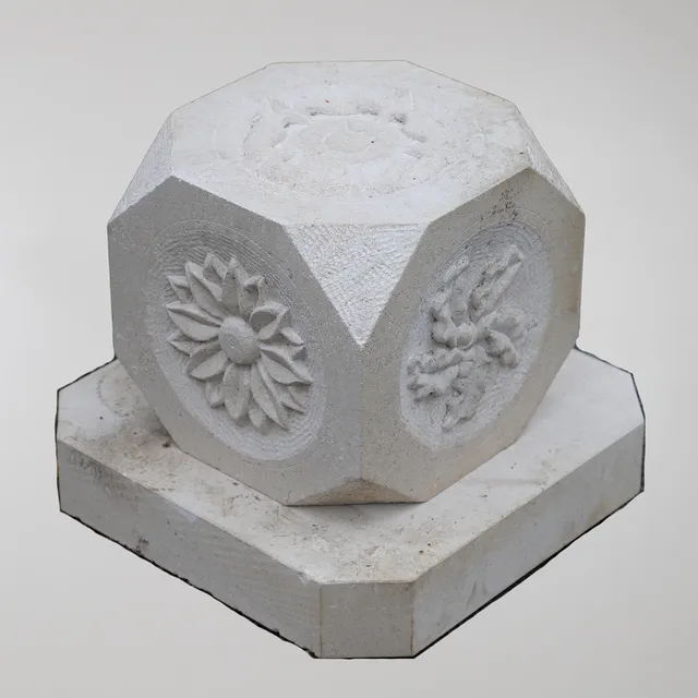 A CARVED LIMESTONE SIX SIDED BLOCK.