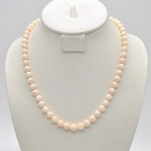 PERLENCOLLIER AUS ENGELSHAUTKORALLE, RUNDE PERLEN, EINZELN GEKNÜPFT, VERGOLDETER VERSCHLUSS, UM 1950, LÄNGE CA. 51 CM.