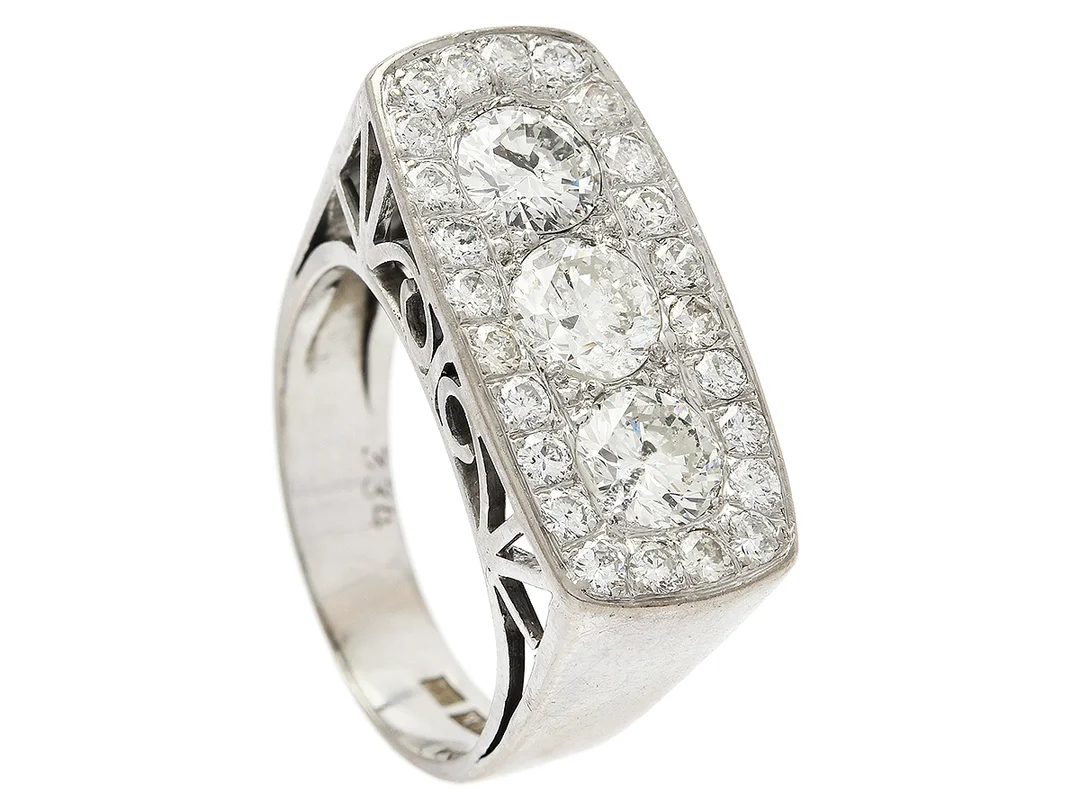 RING, 18K vitguld, 3 briljantslipade diamanter ca 1,65 ctv ca Cr-TCa(J-K)/P1, 24 briljantslipade diamanter ca 0,72 ctv, ca W-Ca/SI-P, Stockholm 1966, stl 17,75 mm, vikt 9,3 g, en liten diamant skadad. — Smycken/Ring — Kaplans