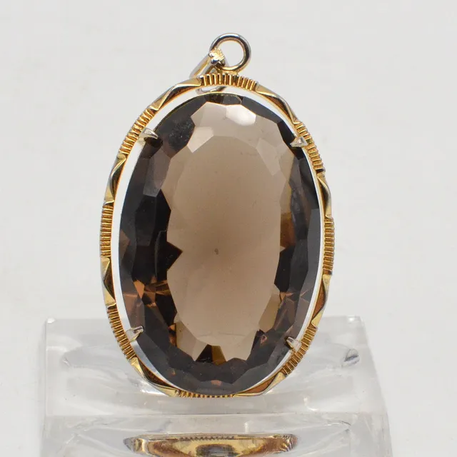 COLLIERANHÄNGER MIT GROSSEM RAUCHQUARZ, OVAL FACETTIERT, VERGOLDETE FASSUNG AUS NEUSILBER, UM 1950.