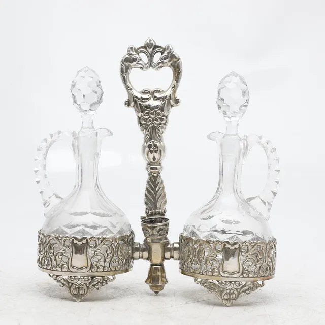 Silvery metal cruets stand with carved glass cruets, 20th Century.