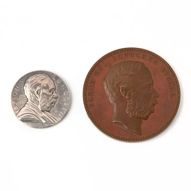 MINNESMEDALJER, "Egron S. Lundgren OB MDCCC LXXV", vitmetall. Samt "Ingenio Clarus Et Arte, MDCCCLXXVI", koppar.