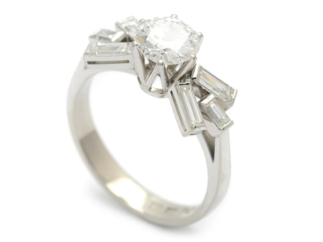 RING, 18K vitguld, mediumslipad diamant ca 1,10 ct, ca TW(F)/mindre skada på undersidan av rondisten, i övrigt små inneslutningar, 6 baguetteslipade diamanter ca 0,74 ctv, ca TW/VS, 2 skadade i paviljongen, nagg på 1 diamant, K. Torndals, Stockholm, stl 17,75+ mm, vikt 5,3 g. — Smycken/Ring — Kaplans