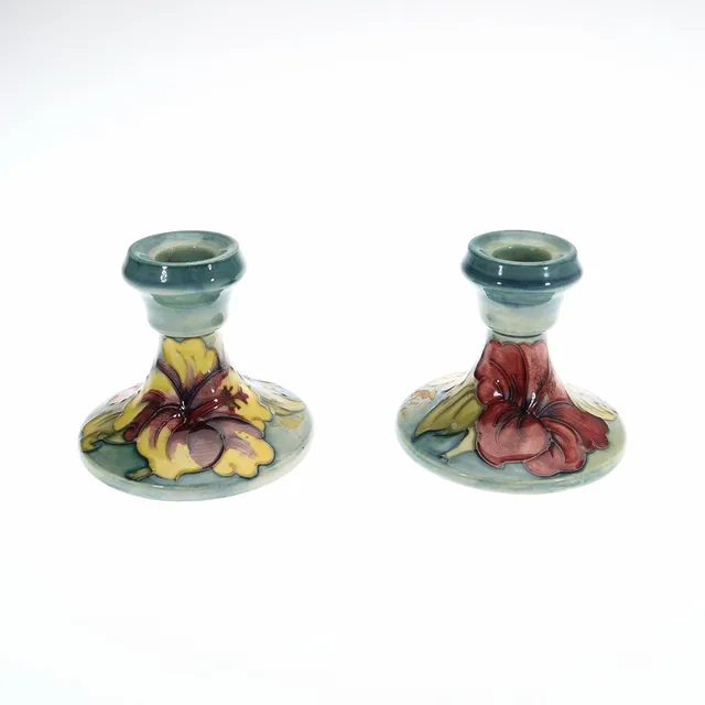 PAIR OF MOORCROFT HIBISCUS PATTERN TUBE LINED DWARF CANDLESTICKS.