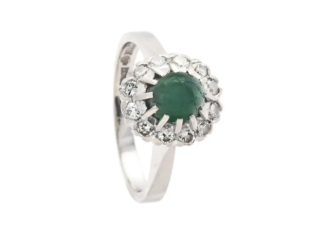 CARMOSÉRING, 18K vitguld, cabochonslipad smaragd, 12 briljantslipade diamanter 0,36 ctv, ca TW/VS, Markströms, Uppsala 1972, stl 17,5 mm, vikt 5,3 g, smaragden med inneslutningar som når ytan.