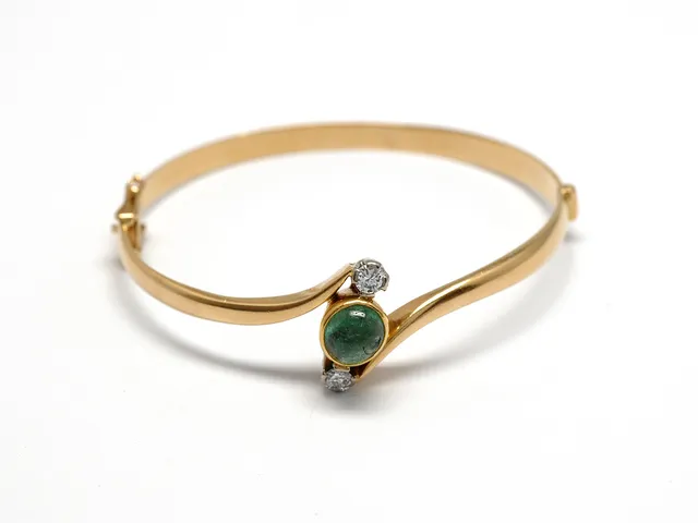 ARMRING, 18K guld, smaragd, skadad, 2 briljanter ca 0,24 ctv, ca W/SI, 5,2 x 4,5 cm, öppningsbar, vikt 14,2 g.