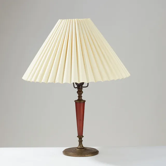 ERIK TIDSTRAND (1876–1944). Table lamp of patinated brass or bronze with a conical stem clad in dark red Pollopas, model no. 26551, Nordiska Kompaniet, Sweden, 1920s.