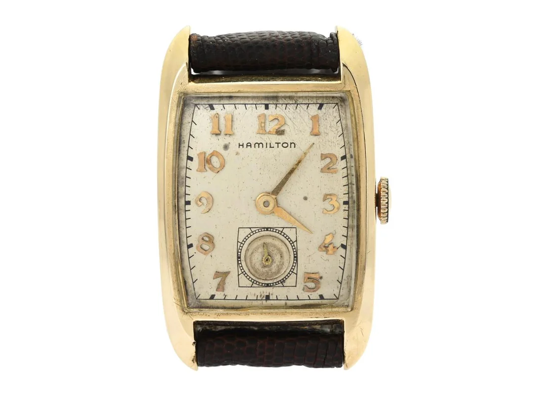 HAMILTON, herrur, 23 x 27 (37,5) mm, Cal 754, Serie nr. 6234H, Boett nr. R243385, 14K guld, manuell, plexiglas, liten sekundvisare, skadad urtavla, formverk, läderband, ca 1952. — Klockor/Hamilton — Kaplans