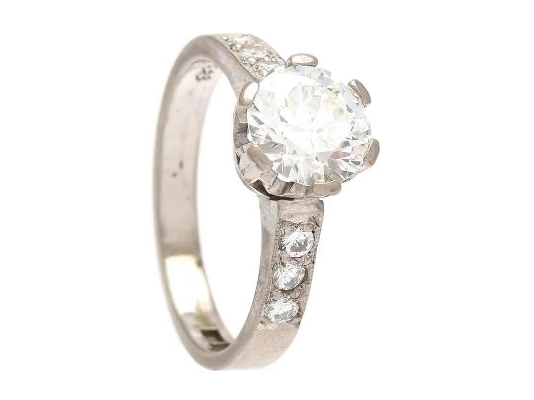 RING, 18K vitguld, äldre briljantslipad diamant ca 1,58 ct, ca R(E) skada och nagg vid rondist i övrigt väldigt små orenheter, tunn rondist, 6 briljantslipade dimanter 0,23 ctv, stl 18 mm, vikt 5,5 g. — Smycken/Ring — Kaplans