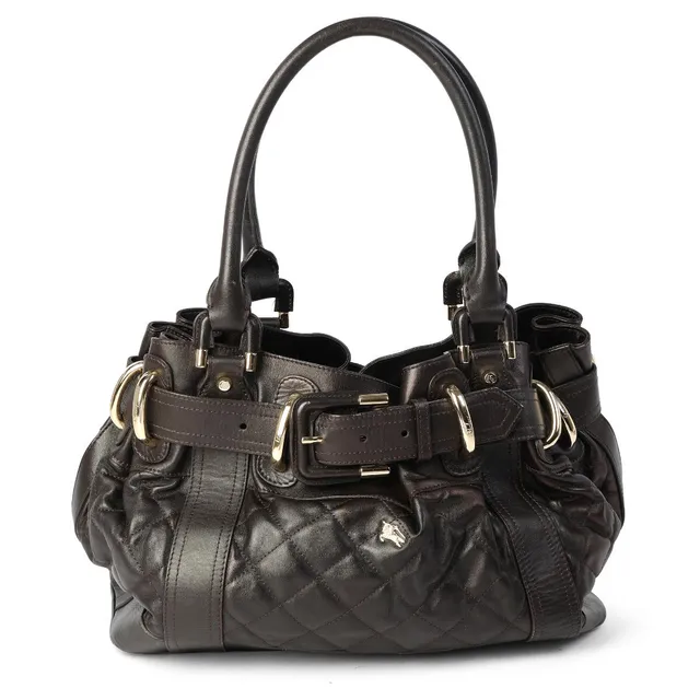A “Beaton Tote” bag of dark brown, quilted leather with gold tone hardware, two handles, one adjustable buckle, one compartment with one middle compartment with a zipper, one zippered pocket, two side pockets and grey nylon lining. H. 25 x W. 38 x D. 18 cm.