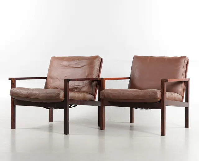DANSK MØBELDESIGN. Et par lænestole med stel af tapsamlet palisander, løse hynder i sæde og ryg, betrukket med læder. Udført i 1960'erne. (2).