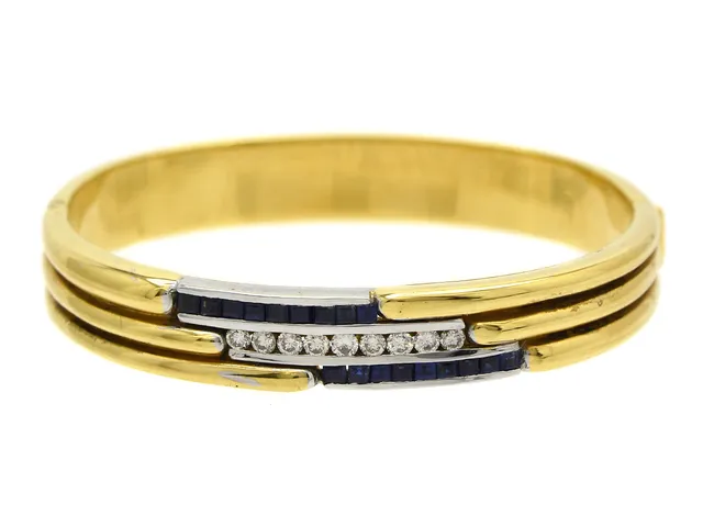 ARMRING, 18K guld, delvis rodierat, 9 briljanter ca 0,50 ctv, ca TCr/VS, 18 safirer ca 0,75 ctv, inre omkrets 16,5 cm, öppningsbart, vikt 46,2 g.G,