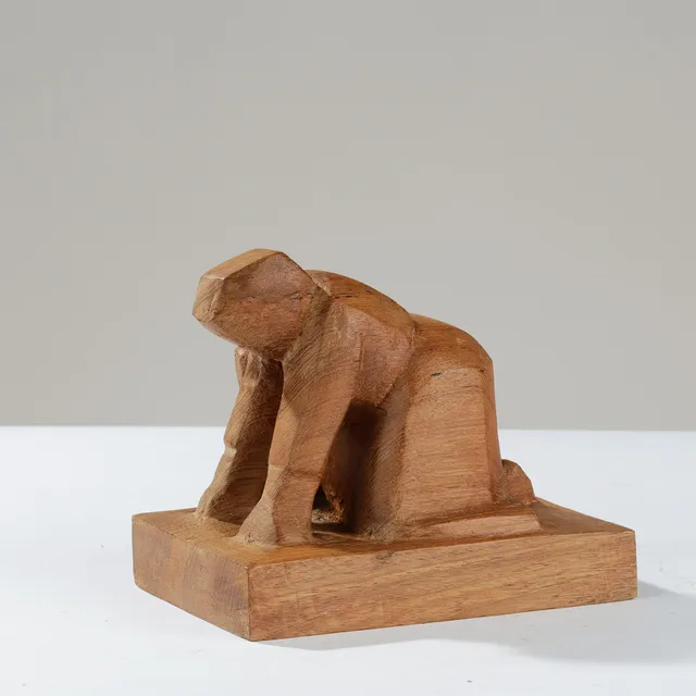 Skulptur af massivt teaktræ forestillende knælende figurskikkelse, antageligt udført af dansk billedhugger i 1900-tallets anden halvdel.