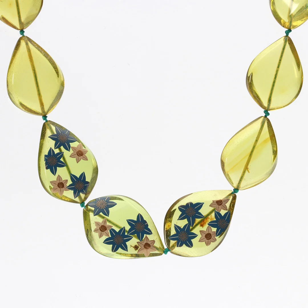 COLLIER, "NY BÄRNSTEN" (Kopal, behandlad), Gröngul med tryckt blomsterdekor. — Necklace — Skånes Auktionsverk