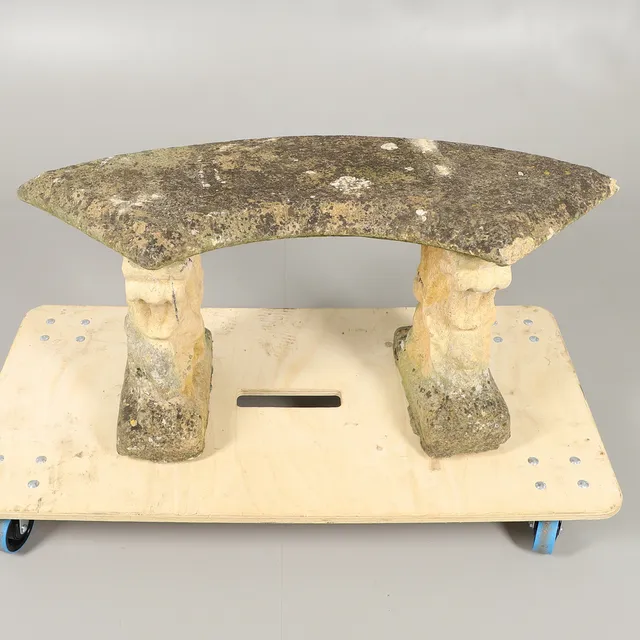 A CURVED RECONSTITUTED STONE BENCH.