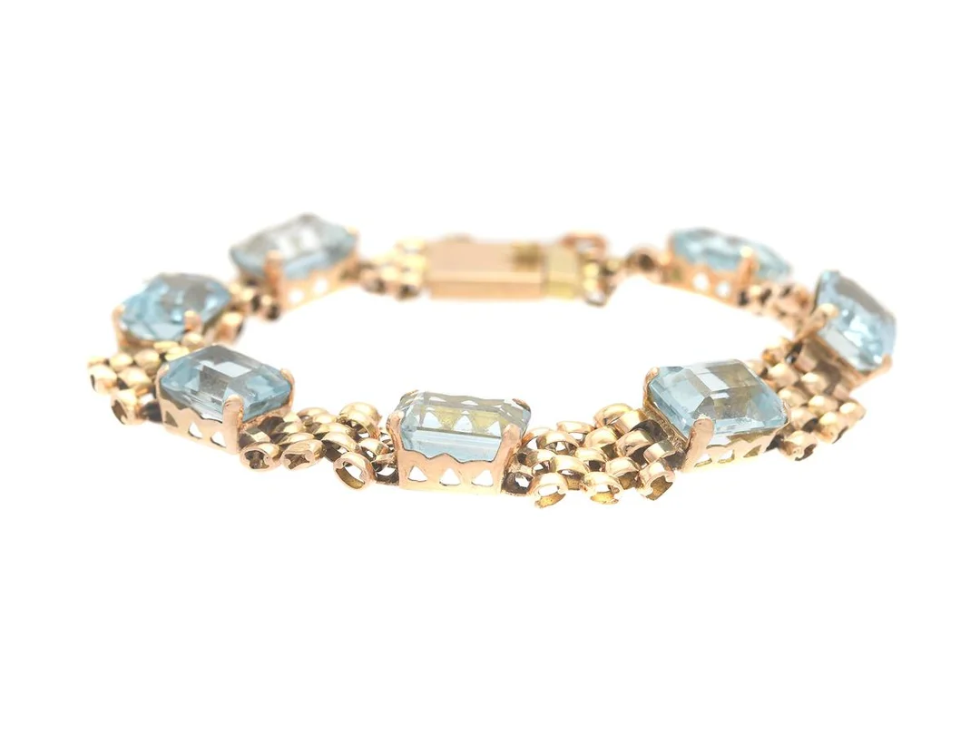 ARMBAND, 18K guld, 7 smaragdslipade akvamariner ca 20 ctv, längd 18 cm, vikt 14,5 g, några akvamariner med nagg och små skador. — Smycken/Armband — Kaplans
