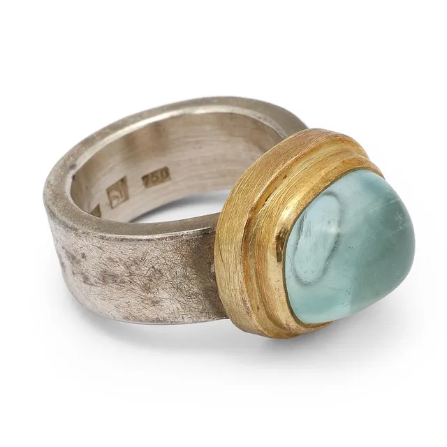 An aquamarine set with a cabochon aquamarine, mounted in silver and 18k gold. Weight app. 22 g. Size app. 53.