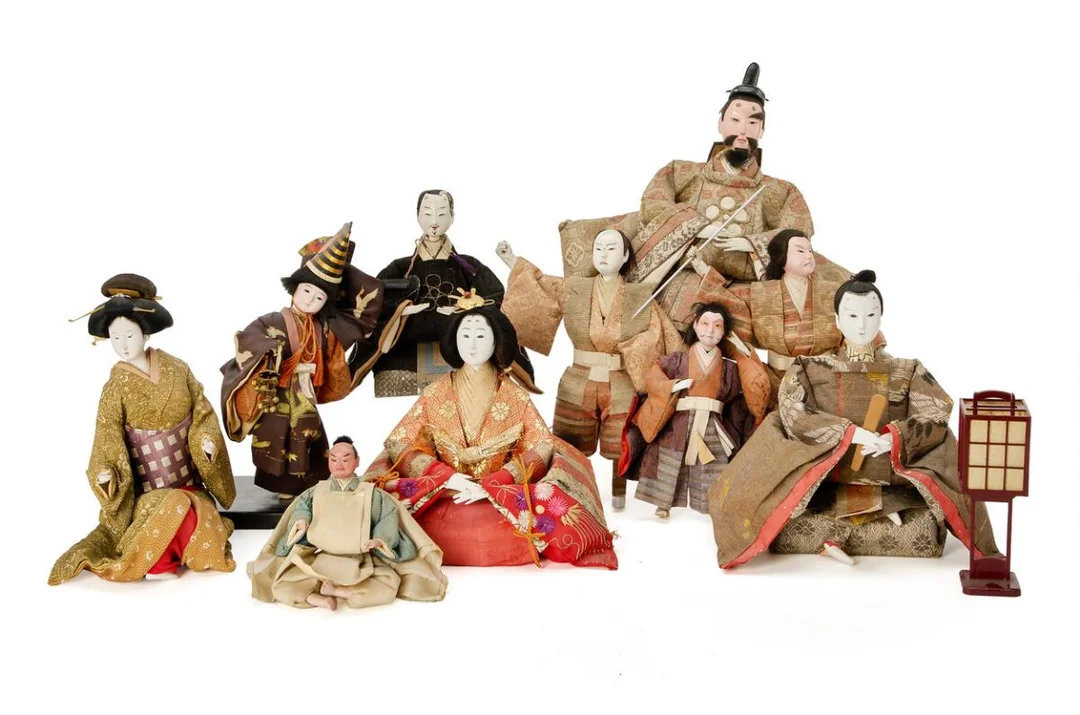 Collection of Japanese dolls comprising various types, including samurai, concubine, emperor and empress, dressed in silk brocade, together with a freestanding lamp. 20th century. H. 14–c. 32 cm. (11) — Asian decorative art — Bruun Rasmussen