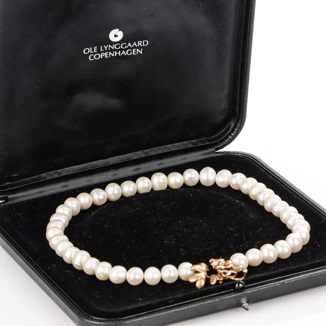 Ole Lynggaard. Flower clasp of 18 kt gold, with freshwater cultured pearl chain.