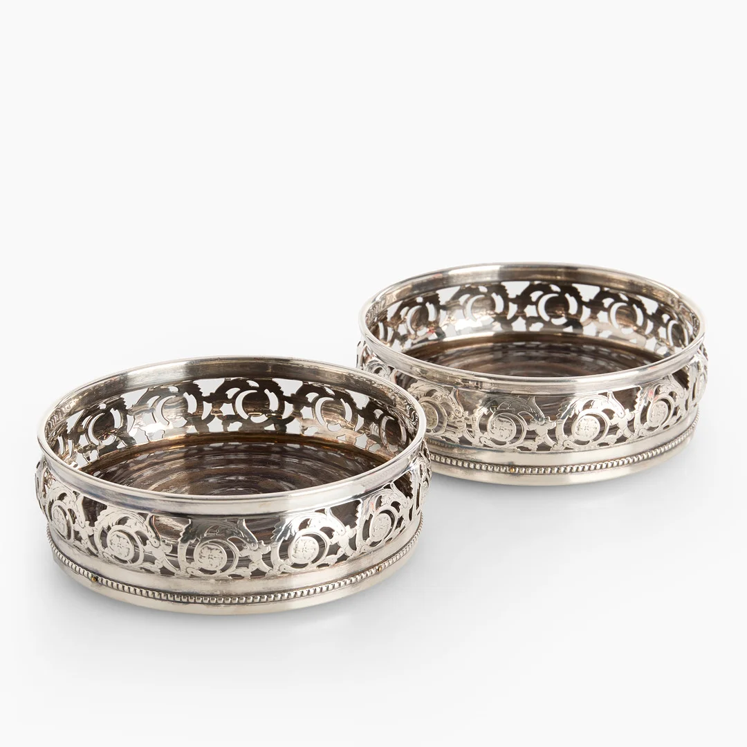 COASTERS, ett par, för Champagnefaskor (Magnum), Württembergische Metallwarenfabrik (WMF), tidigt 1900-tal. Nysilver. Botten i svarvat trä. — Silver plated — Crafoord Auktioner Stockholm