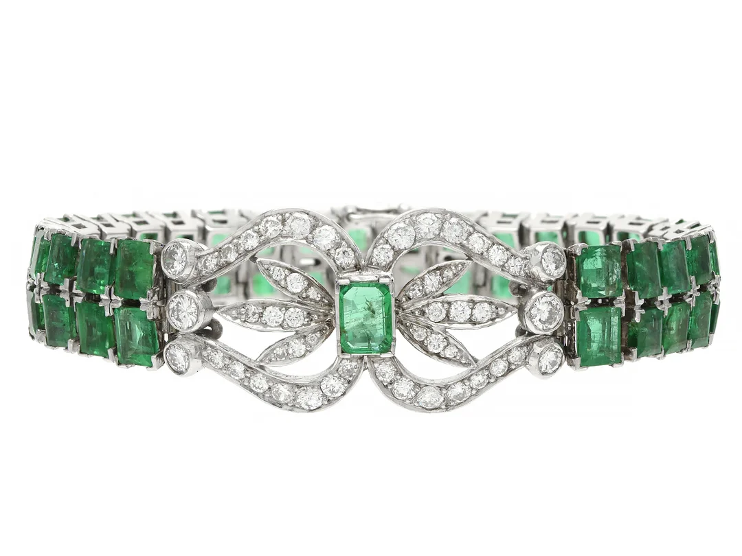 ARMBAND, 18K vitguld, 53 smaragd- och carréslipade smaragder ca 11,00 ctv, 52 briljant- och åttkantslipade diamanter ca 1,50 ctv, ca TW-TCa/VS-P, E.A. Thomasson, Stockholm 1964, längd 15,5 cm, vikt 28,6 g, etui, två diamanter och flera smaragder har nagg och skador. — Smycken/Armband — Kaplans