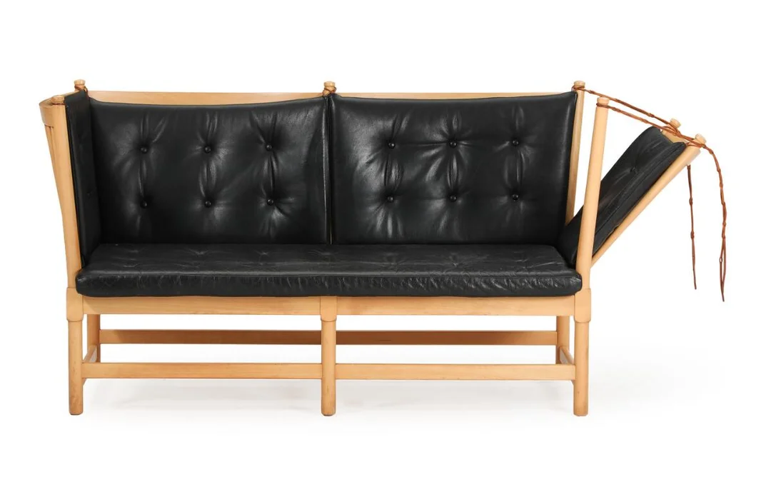 “The spoke-back sofa”. Two-seater sofa with beech frame, pull-out side and back with spokes, loose cushions in seat and back upholstered with black leather. Model 1789. Designed 1945. Manufactured by Fritz Hansen. L. 160 cm. — Modern Furniture — Bruun Rasmussen