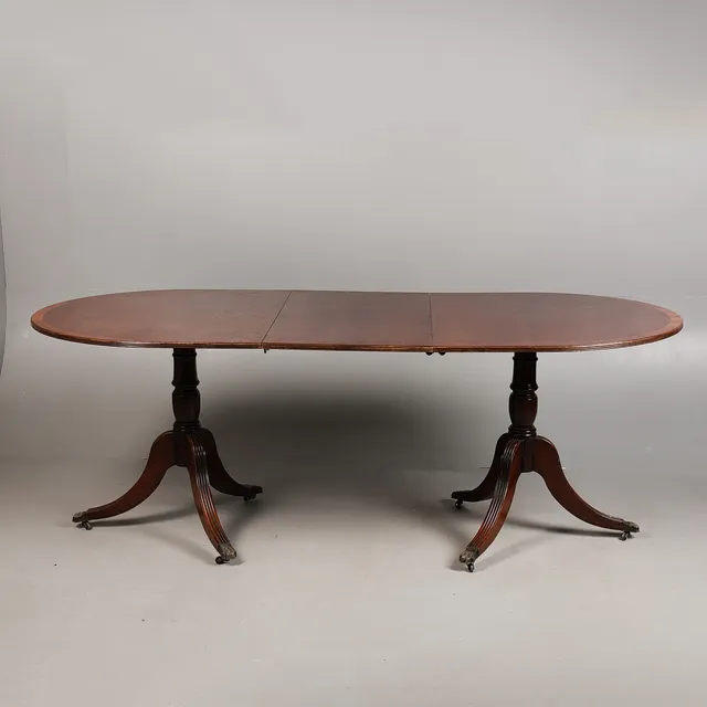A GEORGE III STYLE MAHOGANY TWIN PEDESTAL DINING TABLE.