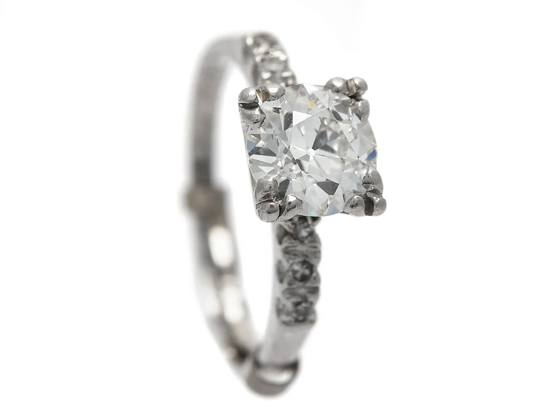 ENSTENSRING, platina, 1 mediumslipad diamant ca 1,20 ct, ca W(H-G), skena med 6 åttkantsslipade diamanter ca 0,05, stl 16,50 mm (med storleksskena), vikt 3,9 g, diamant med nagg och mindre skada på rondisten, tunn rondist, i övrigt endast små inneslutningar, gravyr. — Smycken/Enstensring — Kaplans
