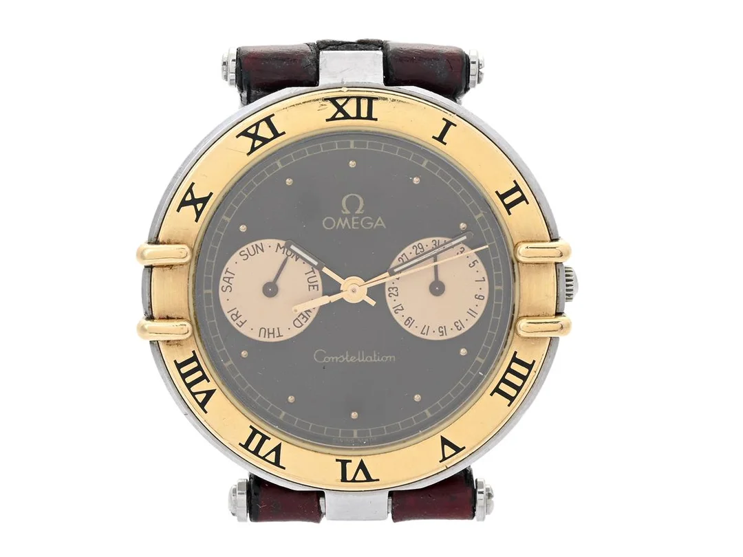 OMEGA, Constellation, s.k. "Uggla", Cal 1444, Serie nr. 50667822, Ref nr. DB 196.1070, Boett nr. 196.1070 (LL), herrur, 33 mm, stål/guld, quartz, safirglas, dag, datum, skadad urtavla/visare, defekt (går ej), integrerat läderband, ca 1987. — Klockor/Omega — Kaplans