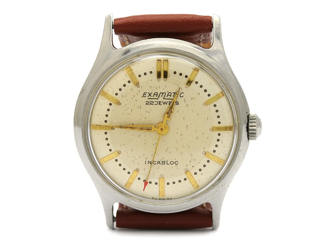 EXAMATIC, herrur, 32,5 mm, vitmetall, automatisk, plexiglas, skadad urtavla, läderband, ca 1960. — Klockor/Övriga klockor — Kaplans