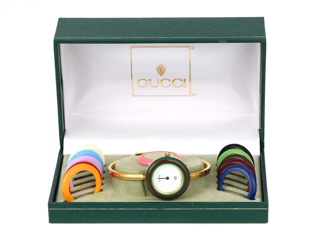 GUCCI, damur, 26 mm, Serie nr. 0821082, Boett nr. 11/12, doublé, quartz, mineralglas, defekt (går ej, akut servicebehov), 12 st. utbytbara ringar, integrerad originallänk, längd 160 mm, ca 1992, box (skadad). — Klockor/Gucci — Kaplans