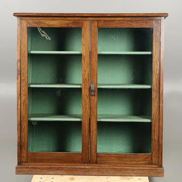 AN EARLY 20TH CENTURY OAK TWO-DOOR GLAZED BOOKCASE.