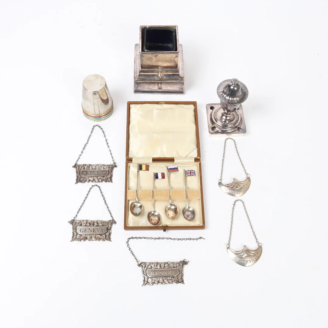 A SILVER PLATED INKWELL, FIVE DECANTER LABELS, FOUR NOVELTY COFFEE SPOONS, FOUR TOT CUPS (8). — Silver plated — Bishop & Miller