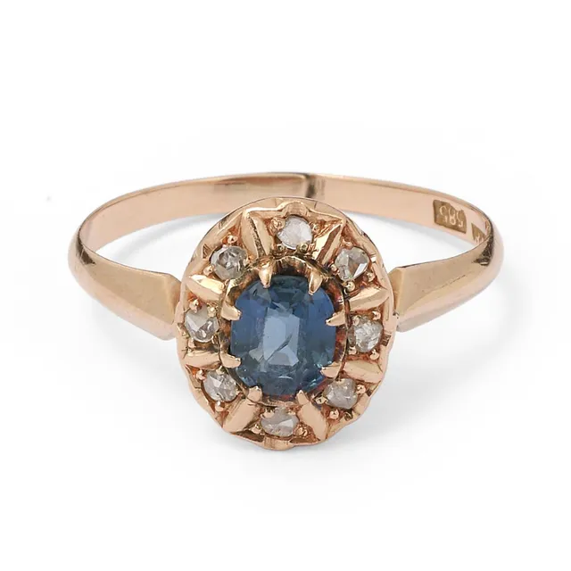 A sapphire and diamond ring set with an oval-cut sapphire encircled by numerous rose-cut diamonds mounted in 14k gold. Weight app. 1.8 g. W. 11 mm. Size 54.