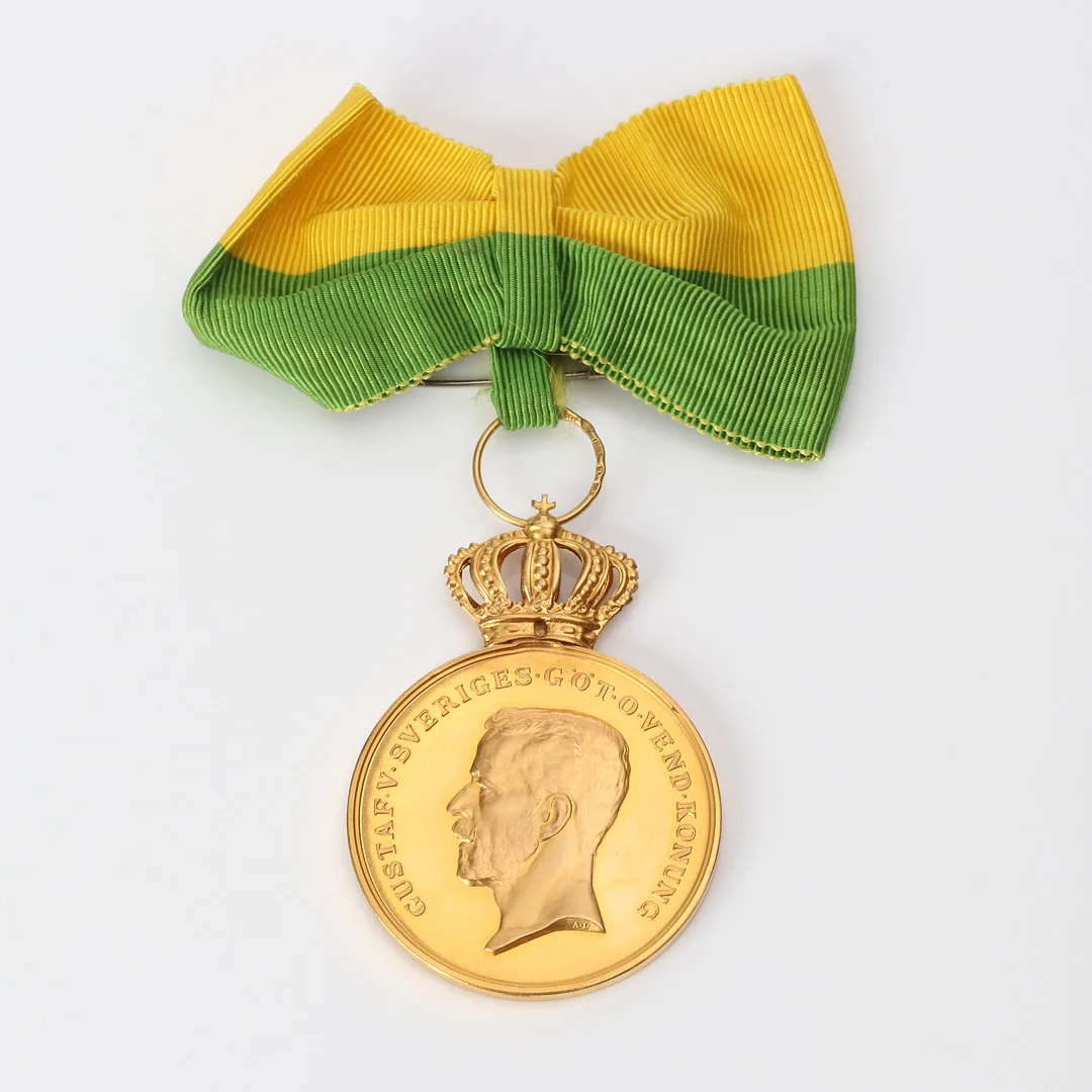 GULDMEDALJ. 23k guld med krona och upphäng i 18k guld, totalvikt inkl. band ca 27,6 gram. — Orders & Medals — Skånes Auktionsverk