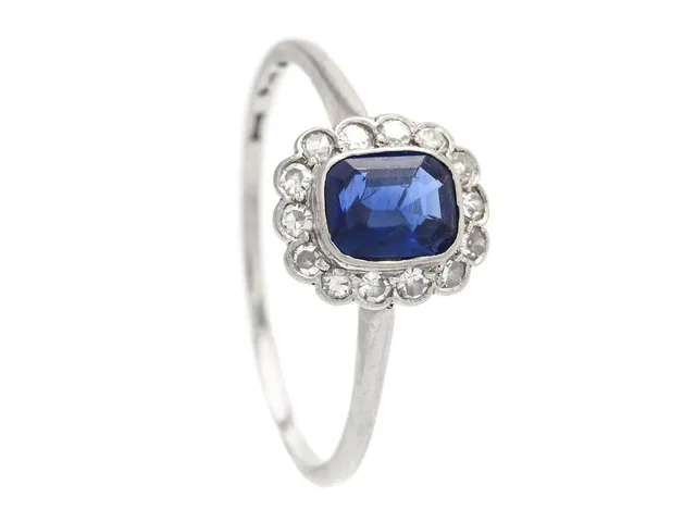 CARMOSÉRING, platina, kuddslipad safir ca 0,60 ct, 14 åttkantslipade diamanter ca 0,15 ctv, stl 19 mm, vikt 2,6 g, tunn ringskena, safiren med en skada.