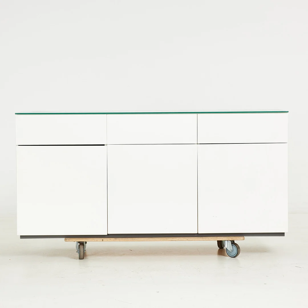 ROLF FRANSSON. Sideboard "Artic" för Voice, vitlackerad mdf, löst liggande glasskiva på toppen, skåpsdelar med bakomliggande hyllplan i glas, tre lådor. — Chests of drawers — Stockholms Auktionsverk Sickla