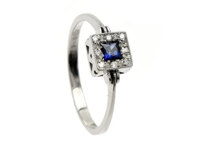 RING, 18K vitguld, blå safir ca 0,25 ct, 8 briljantslipade diamanter ca 0,08 ctv, stl 17,75 mm, vikt 2,3 g, nagg på safirens kulett.